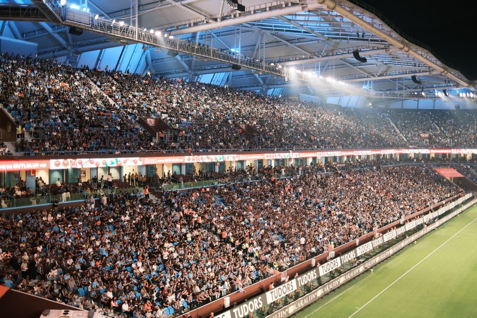Festivais de Música Brasil — Crowd fills a vibrant soccer stadium at night with bright lights and a lively atmosphere.