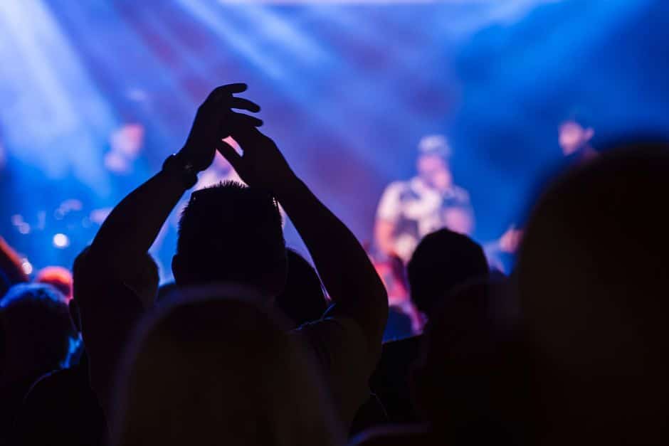 Festivais de Música Brasil — Energetic crowd at a live music concert with vibrant lighting and clapping hands.